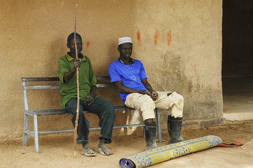 Kokemnoure, Burkina Faso - february 21, 2007: Two friends sit on the bench village Kokemnoure while talking important things of the day.