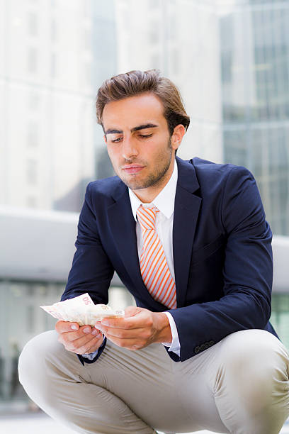 istock Young businessman outside office holding banknotes 466274325