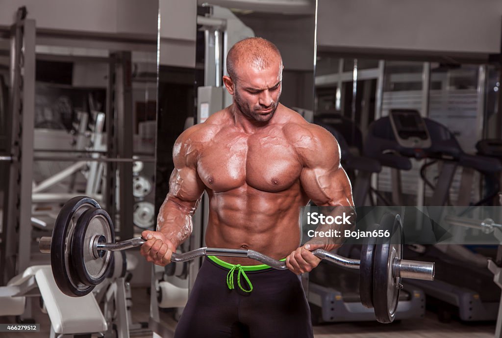 Workout At The Gym Muscular men exercise with weights at the gym. 2015 Stock Photo