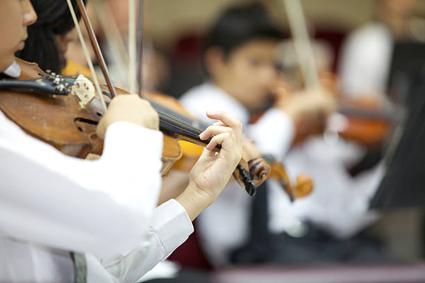молодые violinists маленькая девочка играет с его оркестра. - latin american and hispanic ethnicity child violin music стоковые фото и изображения