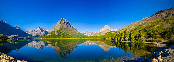 see swiftcurrent lake - woods reflection famous place standing water stock-fotos und bilder