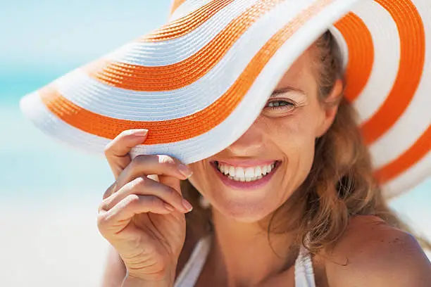 Photo of portrait of happy young woman in swimsuit and beach hat