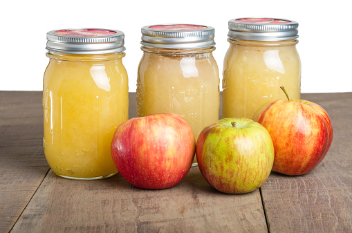 Jars of fresh apple sauce with red apples