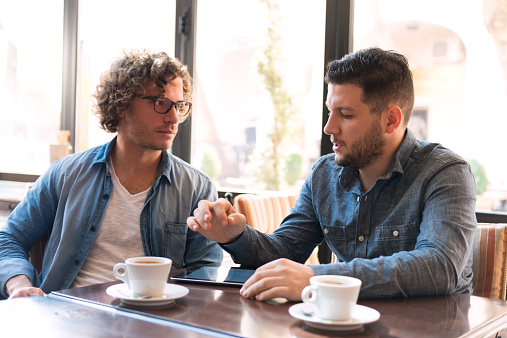 Two young Men Exchange ideas in a Cafe