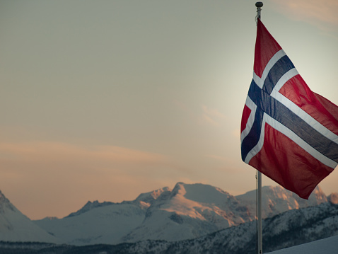 Norwegian flag in front of snow capped mountains