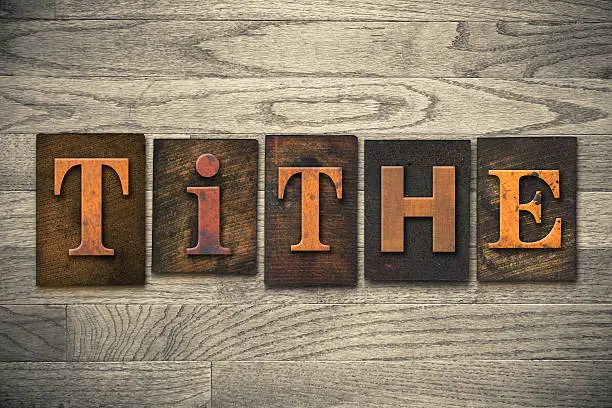 The word "TITHE" written in wooden letterpress type.