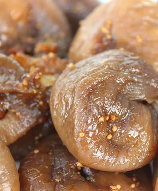 Photo showing some dried figs that have been spread out and pictured close-up, in natural light.  This dried fruit is a popular healthy sweet snack, serving as one of your important 'five a day' of fruit and vegetables, while figs are also known for their health benefits and for being a natural laxative, helping to prevent constipation.