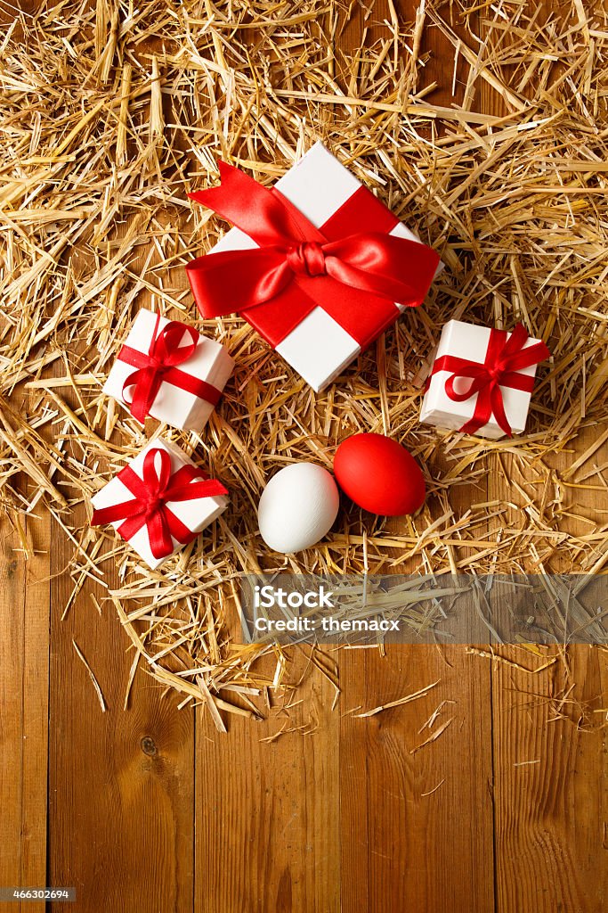 Easter theme - Eggs and gift box Easter theme - Eggs and gift box on straw, wood background. 2015 Stock Photo