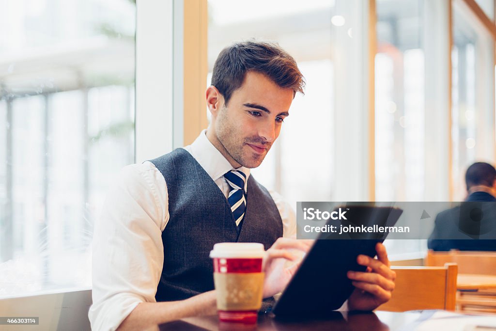 Man in suit with coffee cup and laptop sitting by a window Businessman having a Coffe Break 2015 Stock Photo