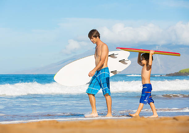 Father and Son Going Surfing Together on Tropical Beach in Hawaii