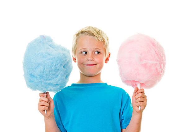 A little boy holding pink and blue cotton candy stock photo