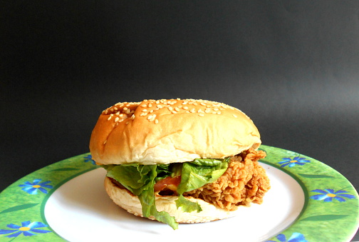 Chicken burger and plate on a black background