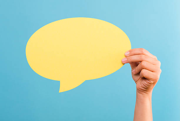 istock Hand holding a yellow text bubble over a blue background 466309500