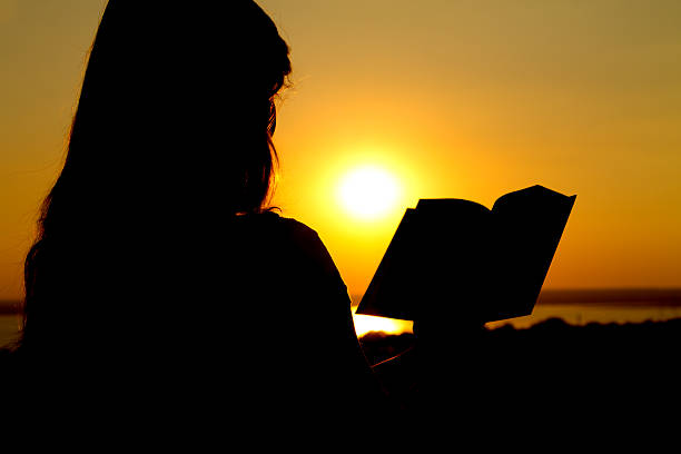 istock silhouette of a girl reading at sunset 466309643