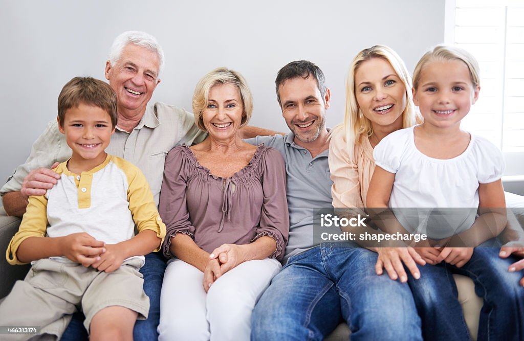 Three generations of smiles Portrait of a smiling three-generational family sitting on their sofa at home 2015 Stock Photo