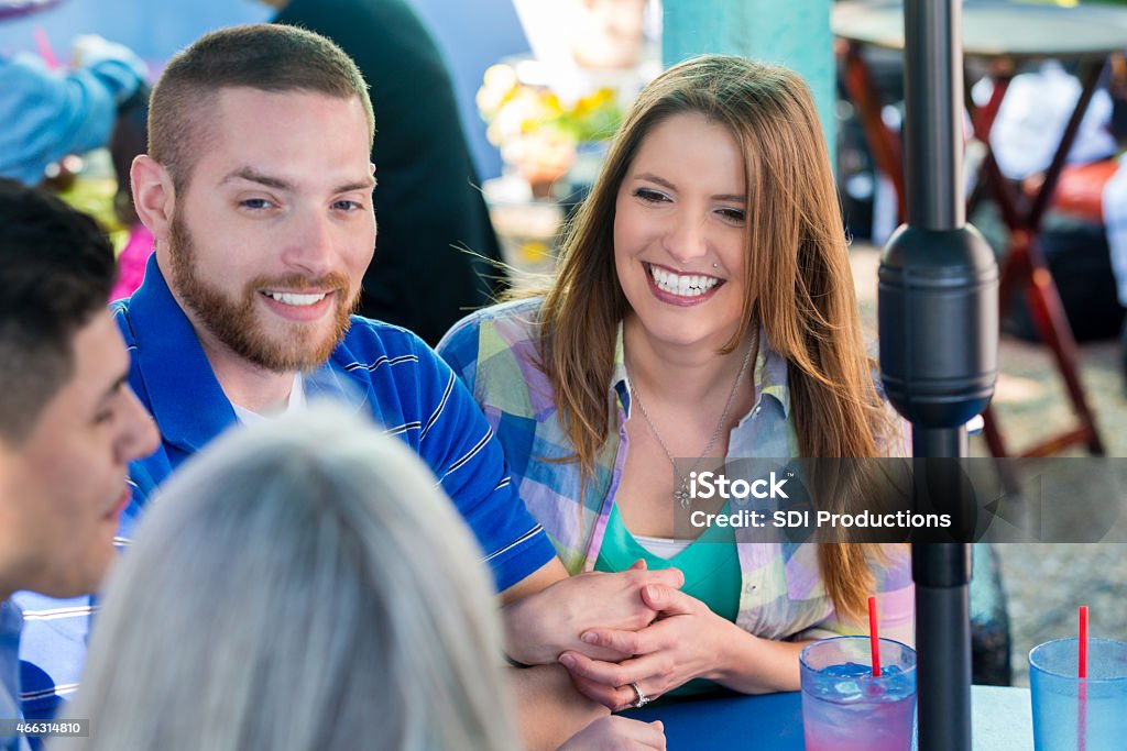 Happy young couple having drinks on restaurant patio with friends 2015 Stock Photo