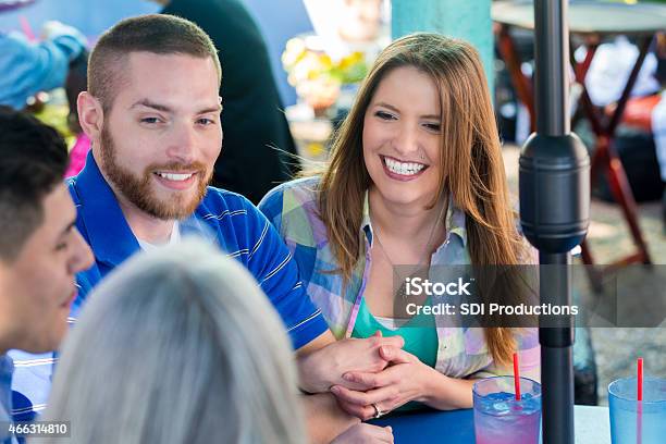 Happy Young Couple Having Drinks On Restaurant Patio With Friends Stock Photo - Download Image Now