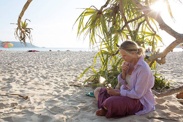istock Woman uses digital tablet in shade area, at beach 466314850