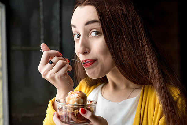 mujer comiendo un helado en la cafetería - women spoon tasting elegance fotografías e imágenes de stock