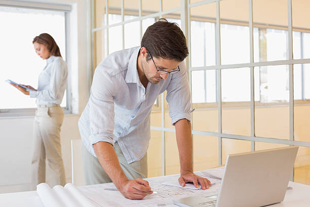 istock Businessman working on blueprints with colleague in background 466316692