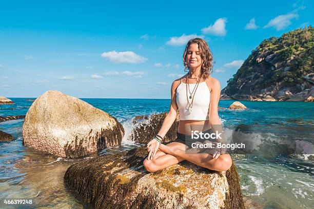 Meditating Woman Sits In Yoga Lotus Pose On Ocean Rock Stock Photo - Download Image Now