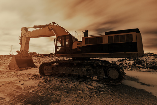 A large excavator on a snowy construction site at night. Long exposure.