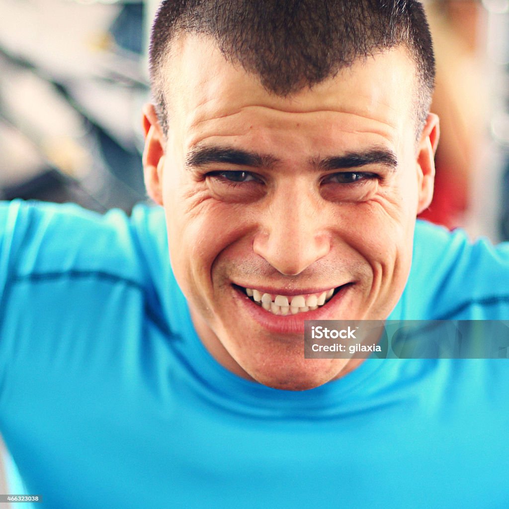 It's hard. Early 30's man with strained facial expression. Actually a closeup crop of gym workout.Wearing blue sport t-shirt. Men Stock Photo