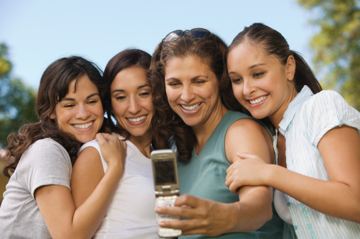 Happy female friends taking self portrait through mobilephone in park