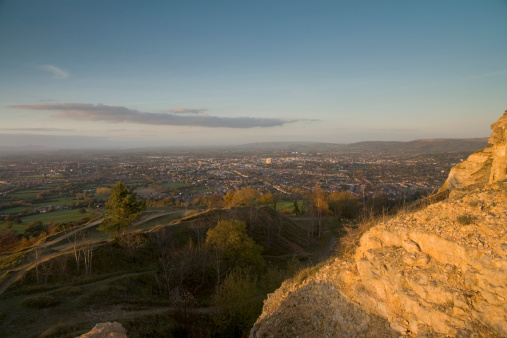 Europe, England, Gloucestershire, Cotswolds, Leckhampton Hill, hillside rocks glowing in the evening sun, view over Cheltenham