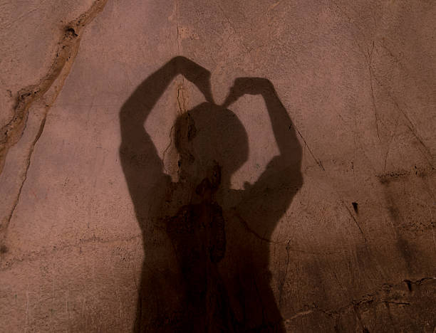 istock two hands forming heart shadow on the wall with cave 466328128