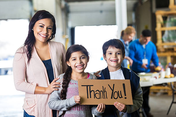 mãe e criança de escola fundamental crianças segurando sinal de agradecimento - charity and relief work donation box thank you child - fotografias e filmes do acervo