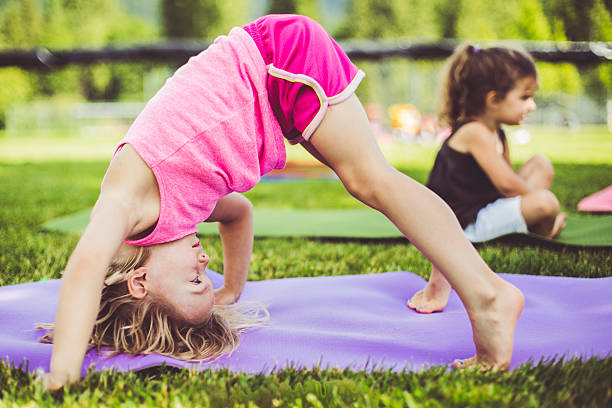 Little girls doing yoga on mats in a park stock photo