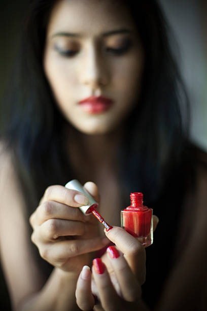 Young woman applying nail polish on her hand nails.