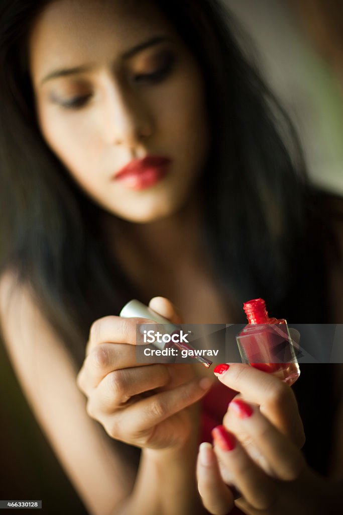 Young woman applying nail polish on her nails. Getting Dressed Stock Photo