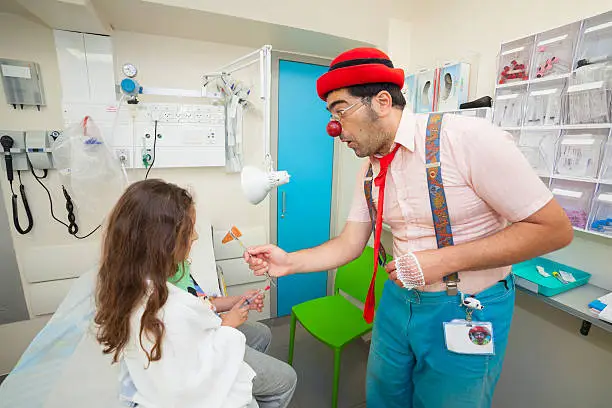 Clown shows a trick to the girl in hospital