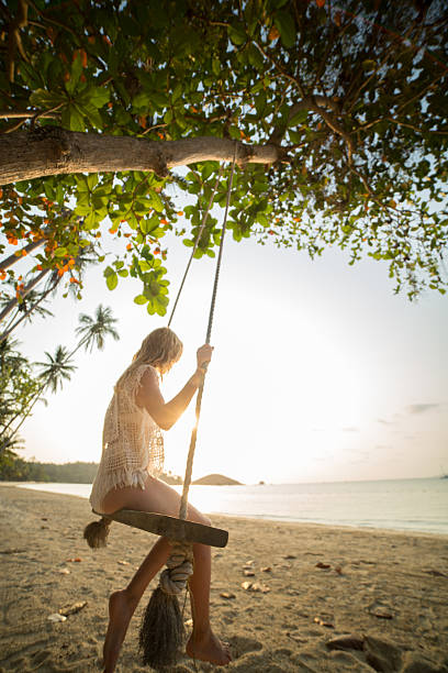 istock Woman sitting on swing watching sunset on beach 466334090