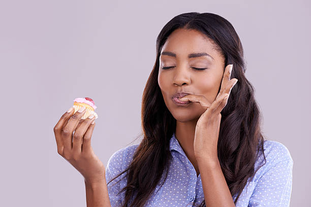 Can't talk, in the cupcake zone Studio shot of a beautiful young woman enjoying a delicious cupcake against a gray backgroundhttp://195.154.178.81/DATA/istock_collage/a13/shoots/785220.jpg dessert sweet food stock pictures, royalty-free photos & images