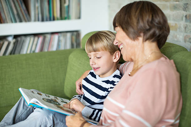 istock Cute little boy reading book with his grandmother 466335610