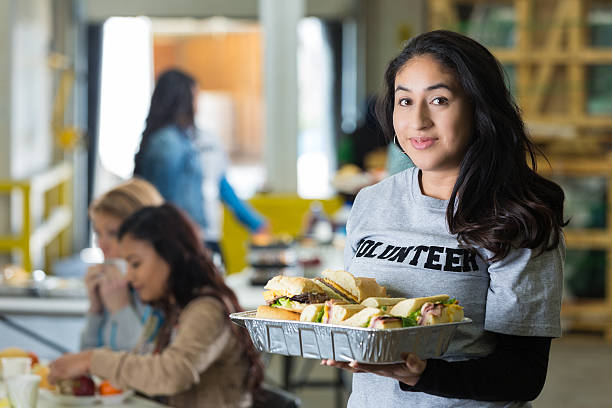 Woman volunteering in food bank, serving lunch to community Woman volunteering in food bank, serving lunch to community soup kitchen stock pictures, royalty-free photos & images