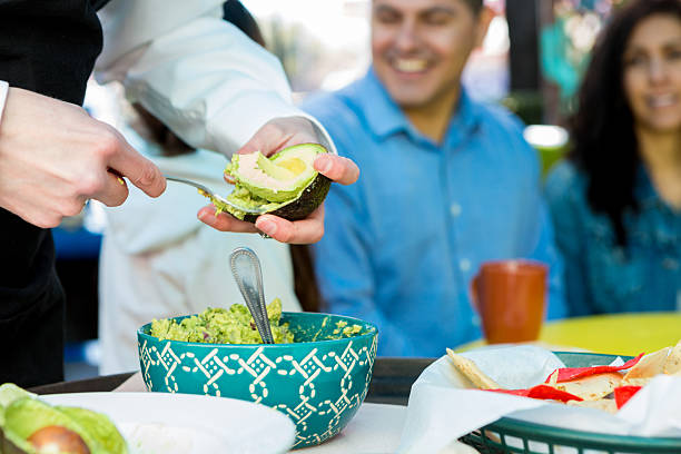 Waitress making table side guacamole for customers in restaurant Waitress making table side guacamole for customers in restaurant guacamole restaurant mexican cuisine avocado stock pictures, royalty-free photos & images