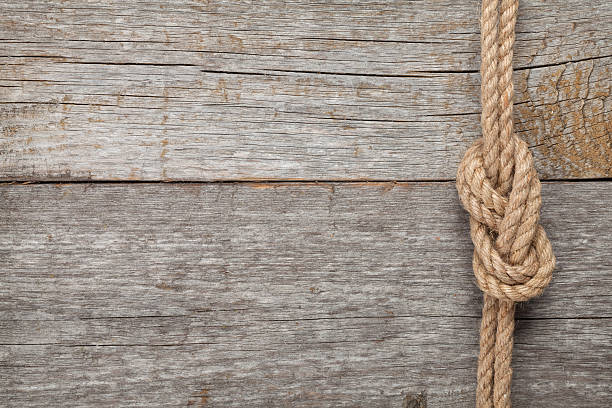 istock Ship rope knot on wooden texture background 466338387