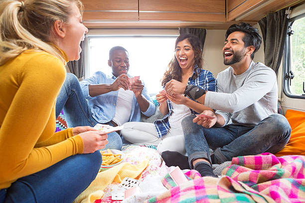 Group of friends having fun playing cards in caravan.