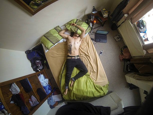 giovane uomo svenuto con letto - hangover alcohol headache student foto e immagini stock