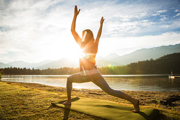 Woman practicing yoga next to a lake stock photo