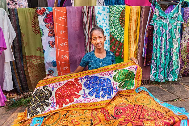 Photo of Young Indian girl selling colorful embroidered rugs