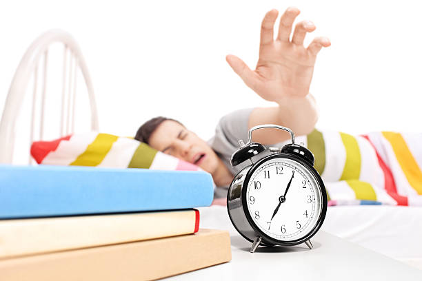 Sleepy man reaching for the alarm clock Sleepy man reaching for the alarm clock isolated on white background smash alarm clock stock pictures, royalty-free photos & images
