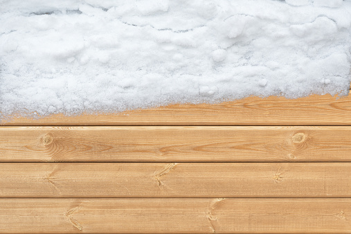 Top view of wooden surface with snow on one side