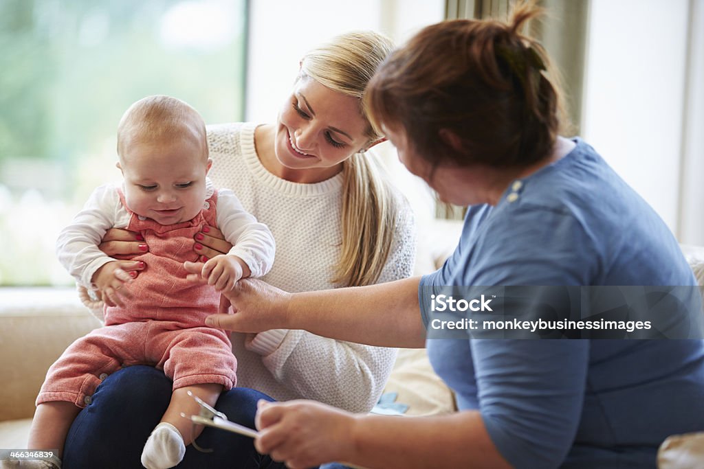 Saúde visitantes jovens falando de mãe com bebê - Foto de stock de Conselho royalty-free