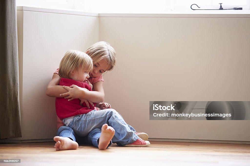 Unhappy Children Sitting On Floor In Corner At Home Unhappy Children Sitting On Floor Holding Each Other In Corner At Home Sibling Stock Photo