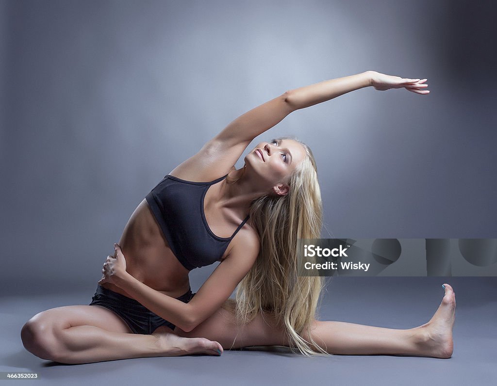 Image of smiling young woman doing stretching Image of smiling young woman doing stretching, on gray background Activity Stock Photo